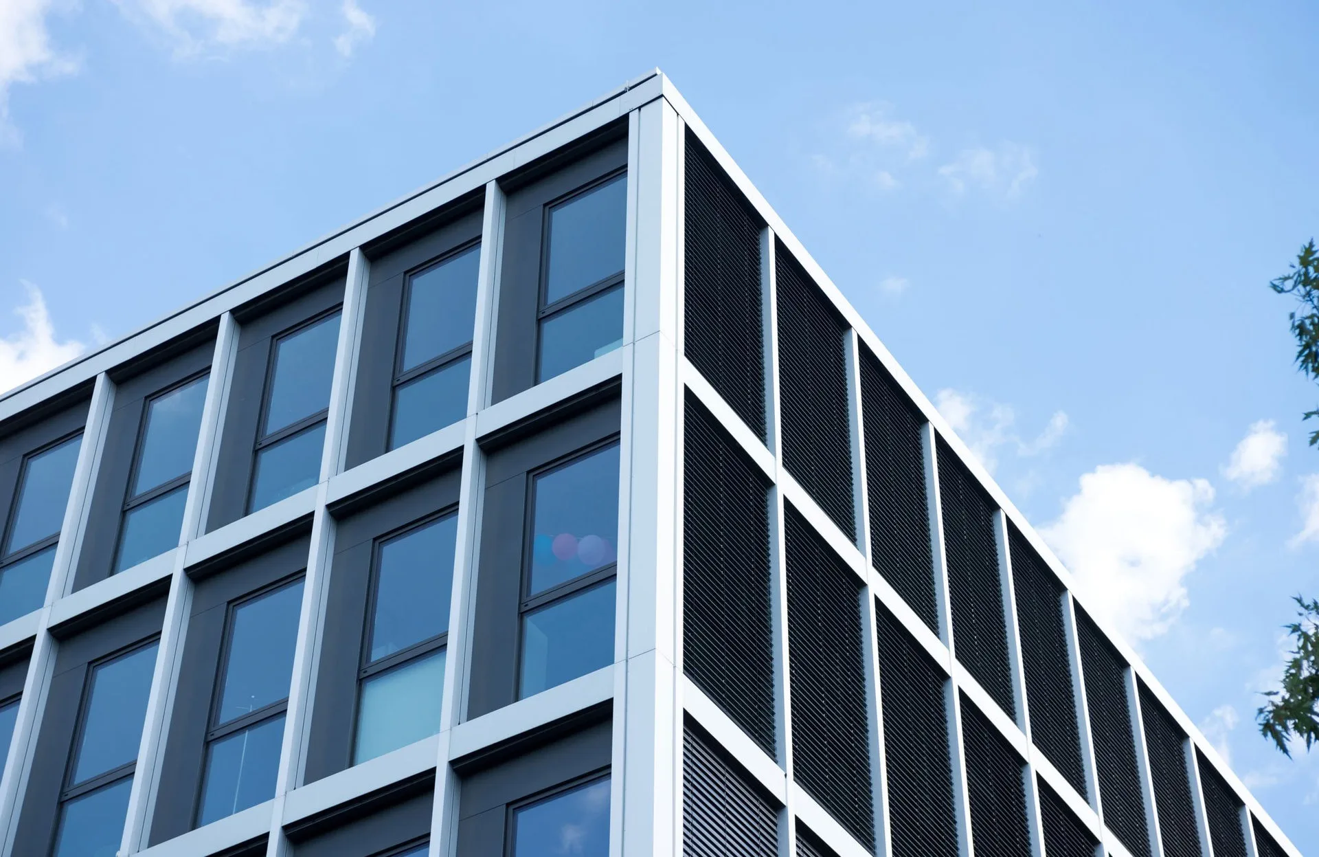Moderne Aluminium-Pfosten-Riegel-Fassade mit Glasfeldern und Sonnenschutz an einem Bürogebäude