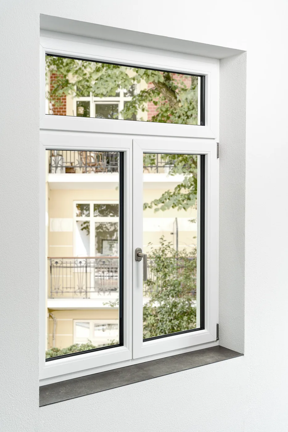 Weißes Kunststoff-Stilfenster mit Oberlicht vor einer Gründerzeitfassade