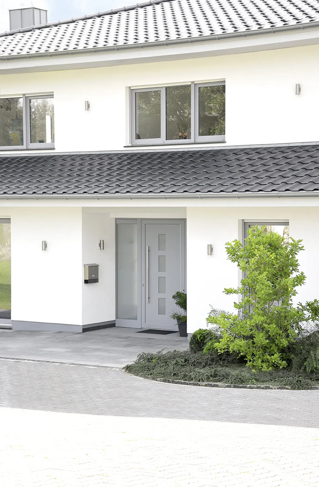 Moderne graue Haustür mit schmalen Glasausschnitten an einem weißen Stadthaus