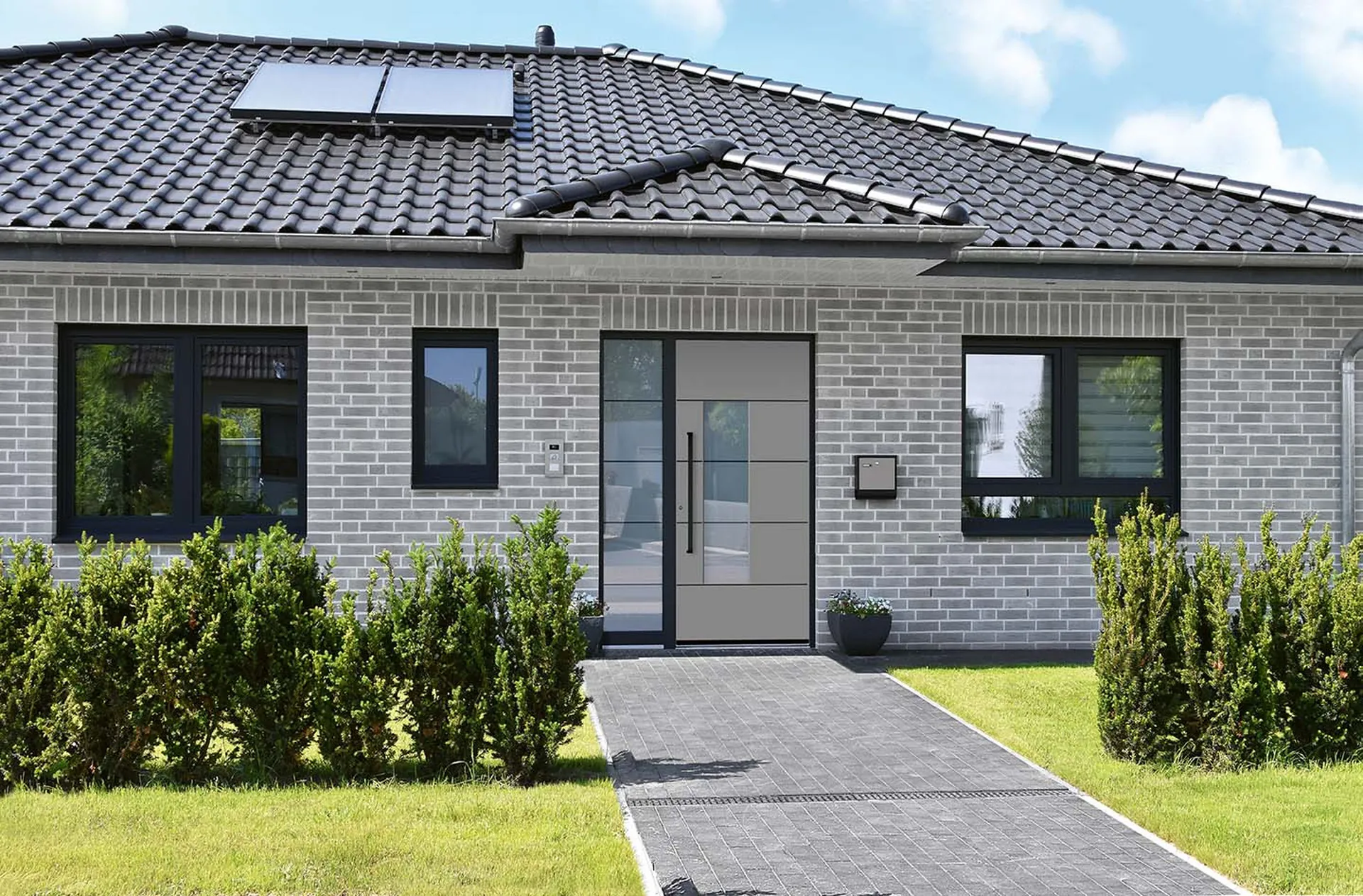 Anthrazitfarbene Haustür mit Seitenteil an einem Klinker-Bungalow